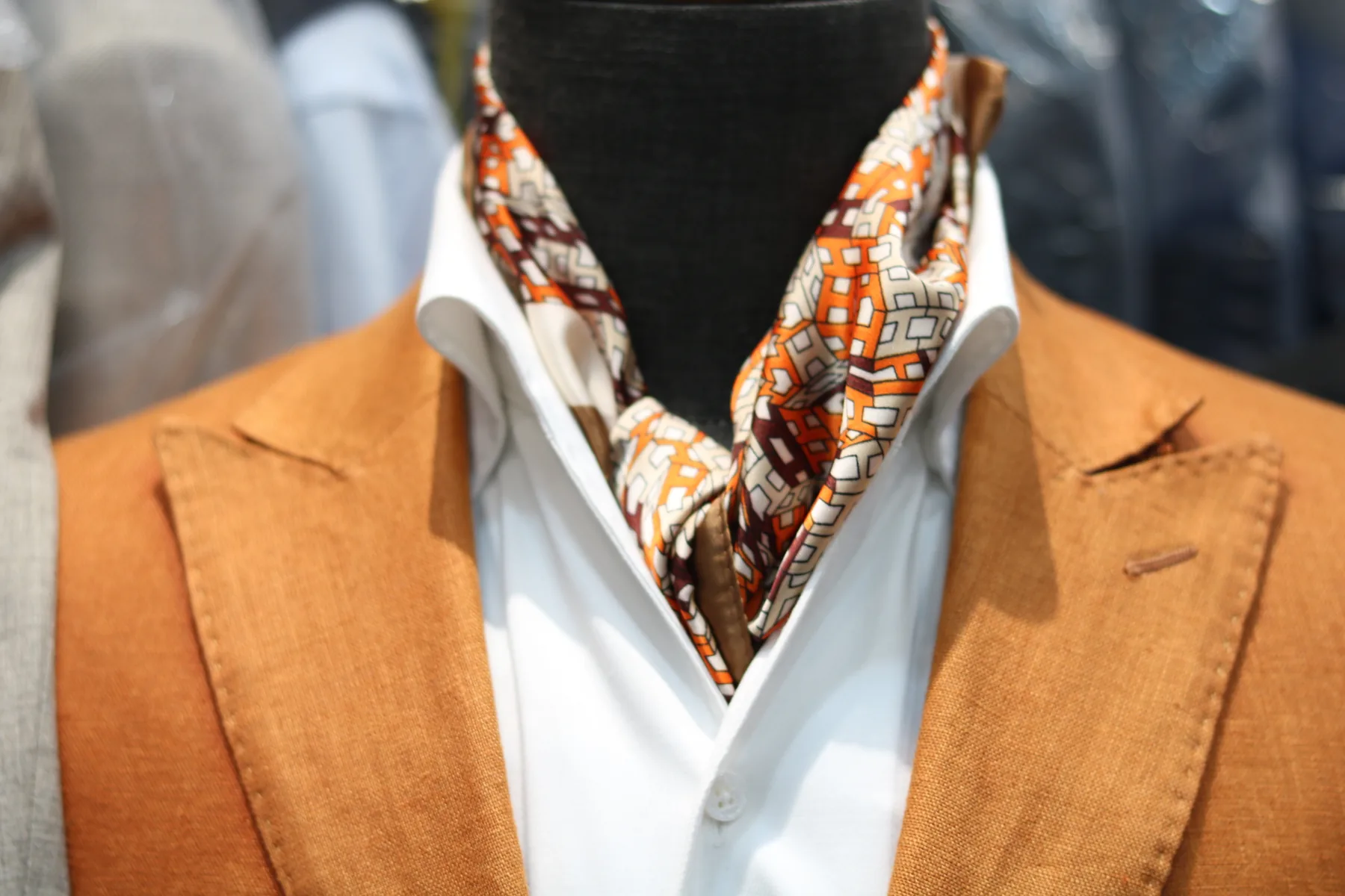 An orange jacket with a white shirt and patterned scarf