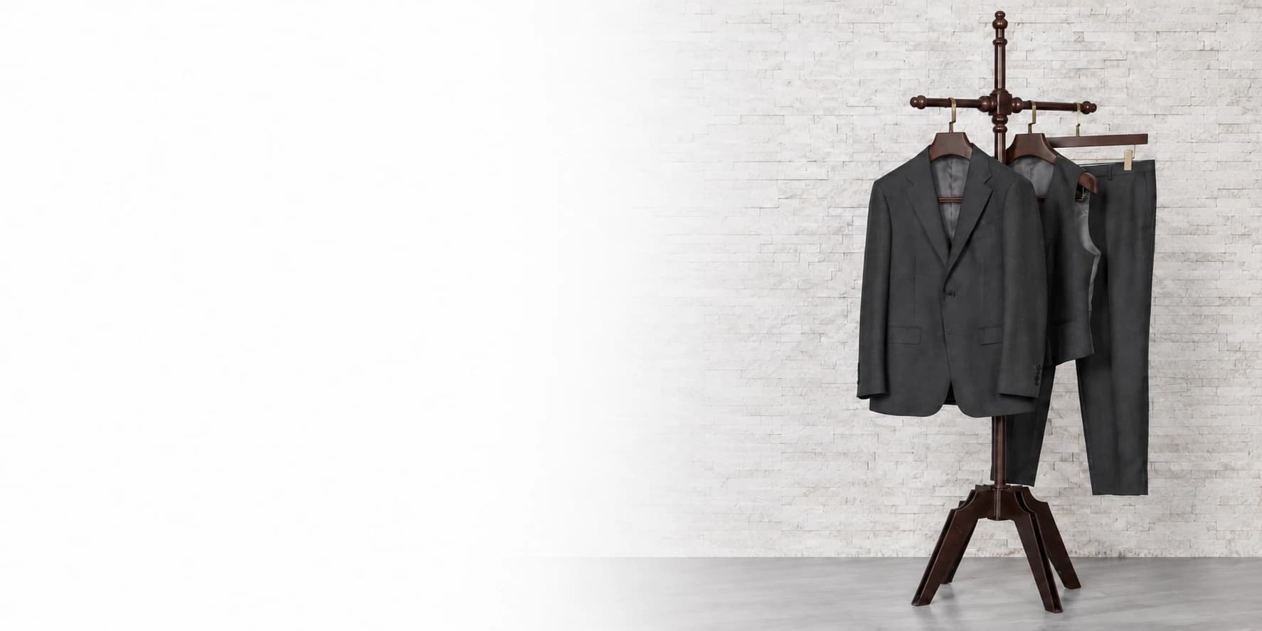 Charcoal three-piece suit and complete wooden tailoring stand against a white backdrop